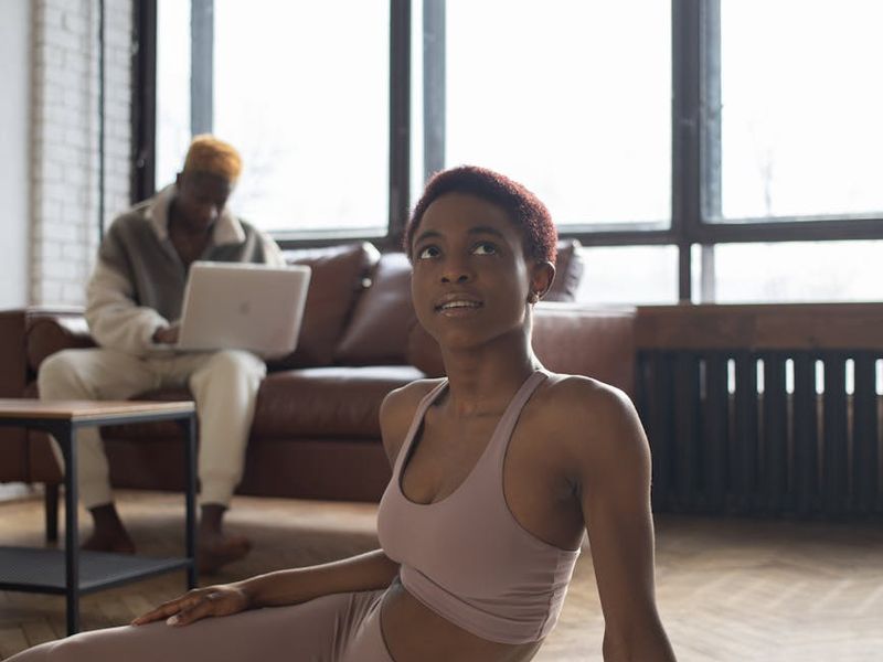 Person doing a stretching exercise in a bright room.